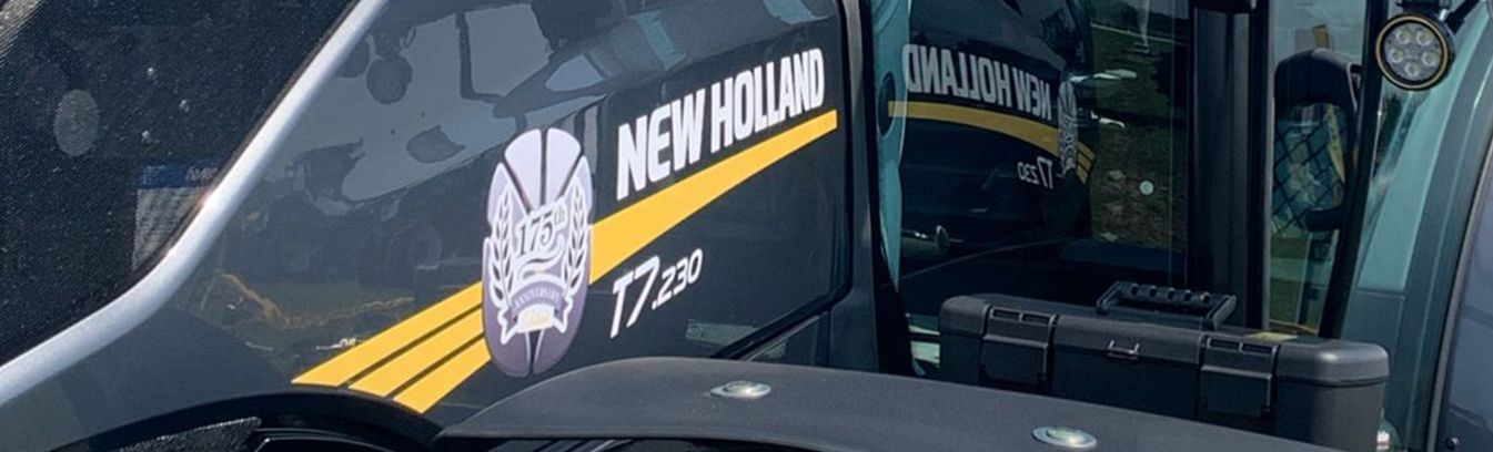 A new holland tractor with a yellow logo on the side showcasing digital printing expertise.