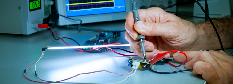 A person is working on a piece of electronic equipment, applying custom medical labels.