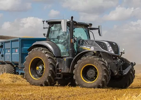 A new holland tractor in a field with high quality labels on the trailer.
