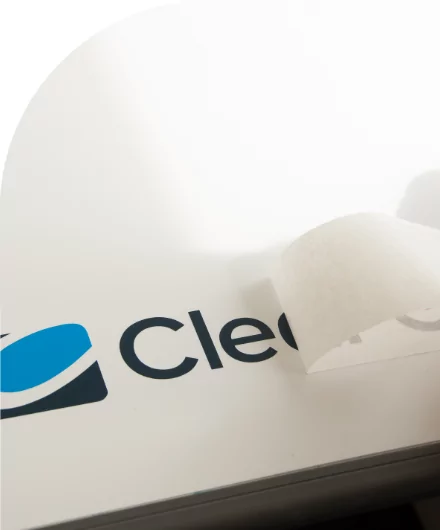 A person cutting a high quality label with the Clearco logo on it.