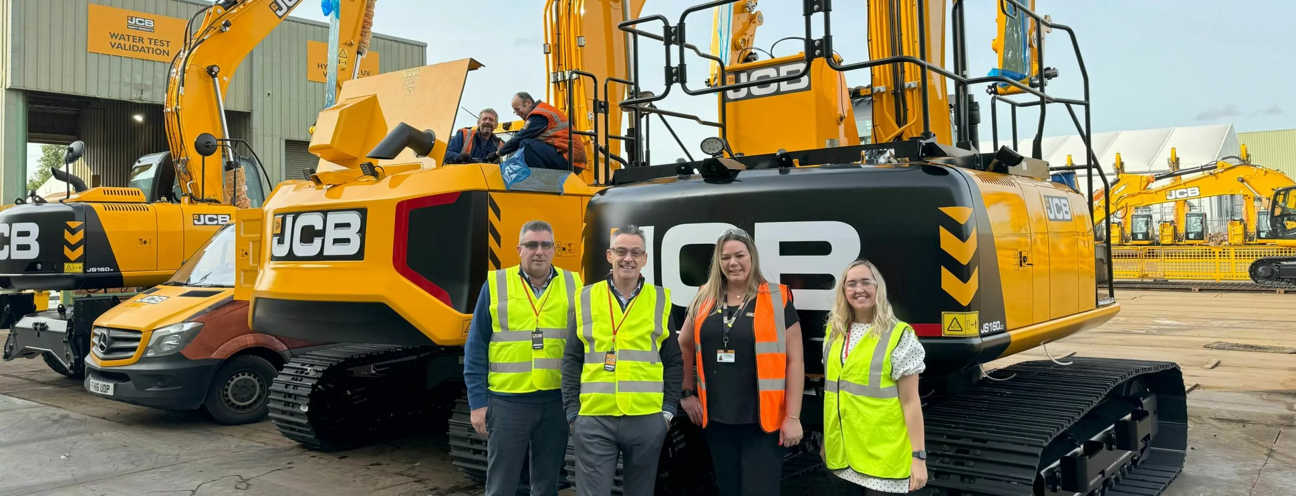 A group of people standing in line in front of a group of construction equipment.