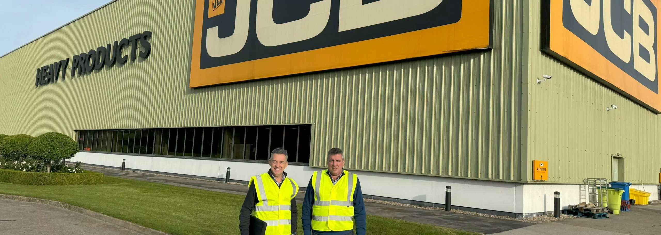 Two men standing in front of a jcb products building.